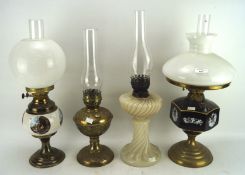 Four 19th/20th century oil lamps with glass, brass and ceramic reserves,