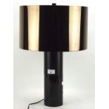 A contemporary table lamp, the brown metallic shade mounted on a ceramic and wooden stand,