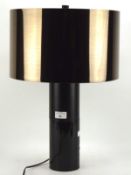 A contemporary table lamp, the brown metallic shade mounted on a ceramic and wooden stand,