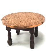 A hammered copper metal coffee table, of circular form, raised upon four turned supports,