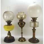 Three Edwardian oil lamps, one with yelllow glass body, all with shades,