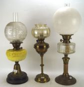 Three Edwardian oil lamps, one with yelllow glass body, all with shades,