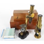 Two antique brass microscopes, within fitted wooden boxes, together with a selection of slides,