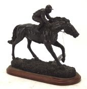 A bronzed figure of a racehorse, mounted on a wooden base,