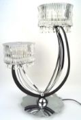 A contemporary chrome and glass table two light lamp, with two branches with glass shades and drops,