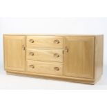 An Ercol light elm sideboard, the three central drawers flanked by panelled doors,