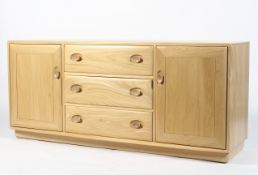 An Ercol light elm sideboard, the three central drawers flanked by panelled doors,