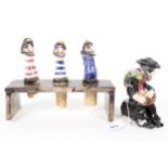 Three West Country Alan Young pottery wine stoppers and stand and a seated pirate