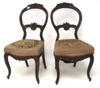 A pair of Victorian balloon back chairs, the mahogany frames with carved floral details,