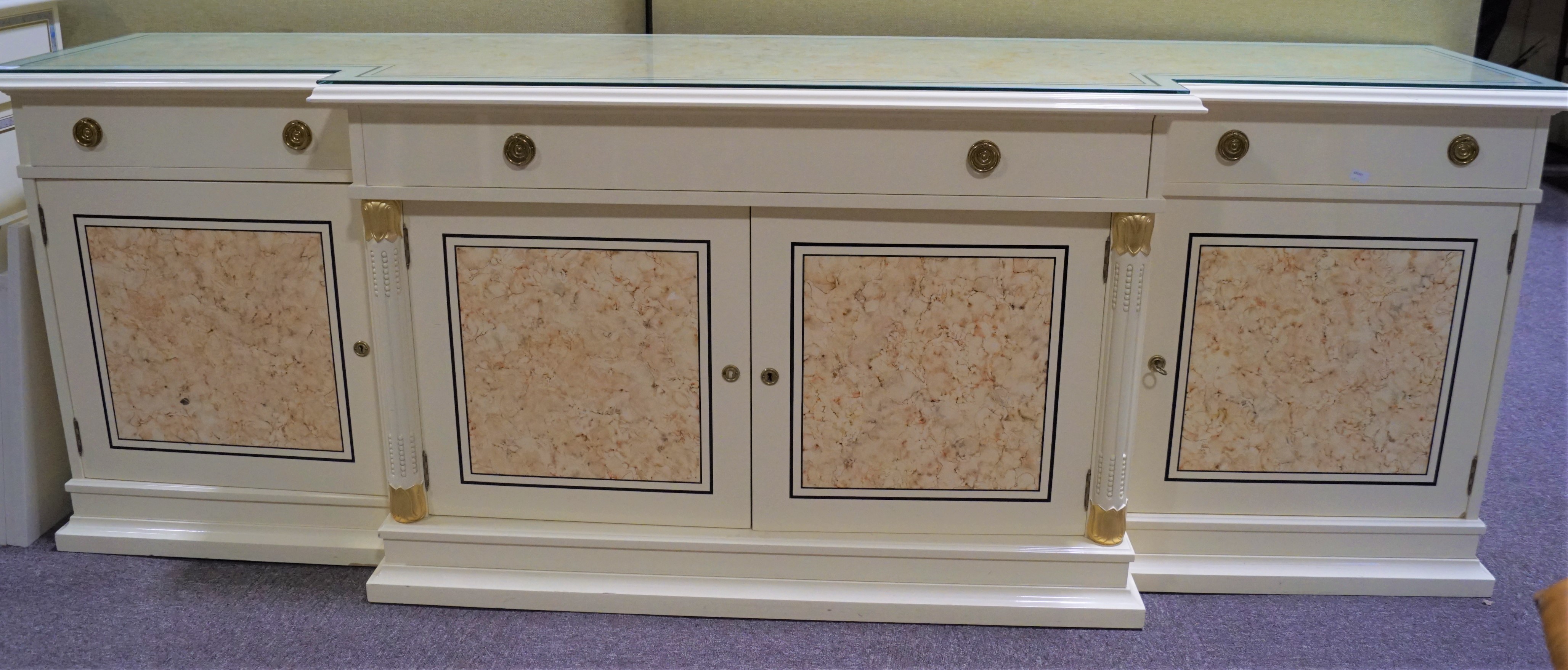 A large cream sideboard of stepped form with two short and one long drawer over cupboards,