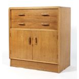 A Maple chest of two drawers, the upper drawer with three sections raised on a cupboard base,