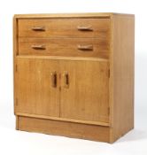 A Maple chest of two drawers, the upper drawer with three sections raised on a cupboard base,