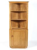 An Ercol blonde elm and beech wood free standing corner cabinet,