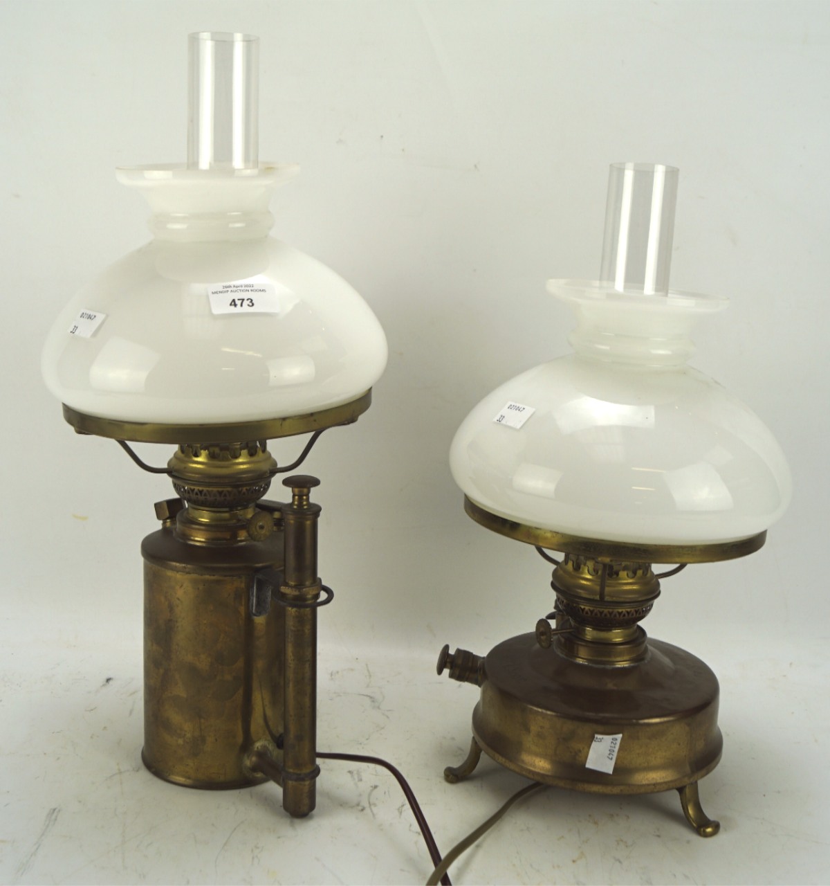 Two adapted brass electrified oil lamps, each with outer white glass shade and clear funnel,