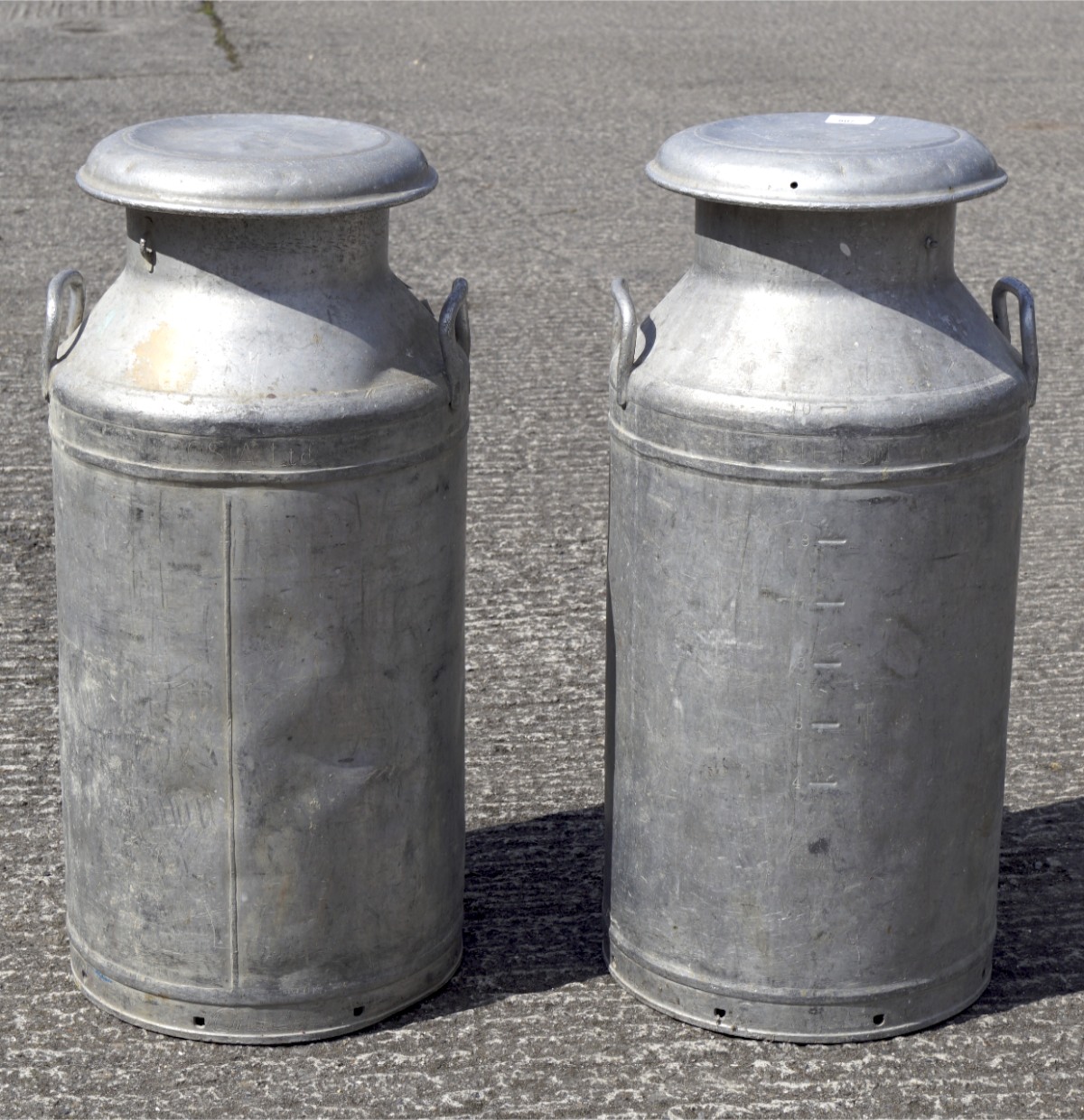 Two vintage aluminum lidded milk churns, both made by Grundy, one marked Horlicks Dairies,