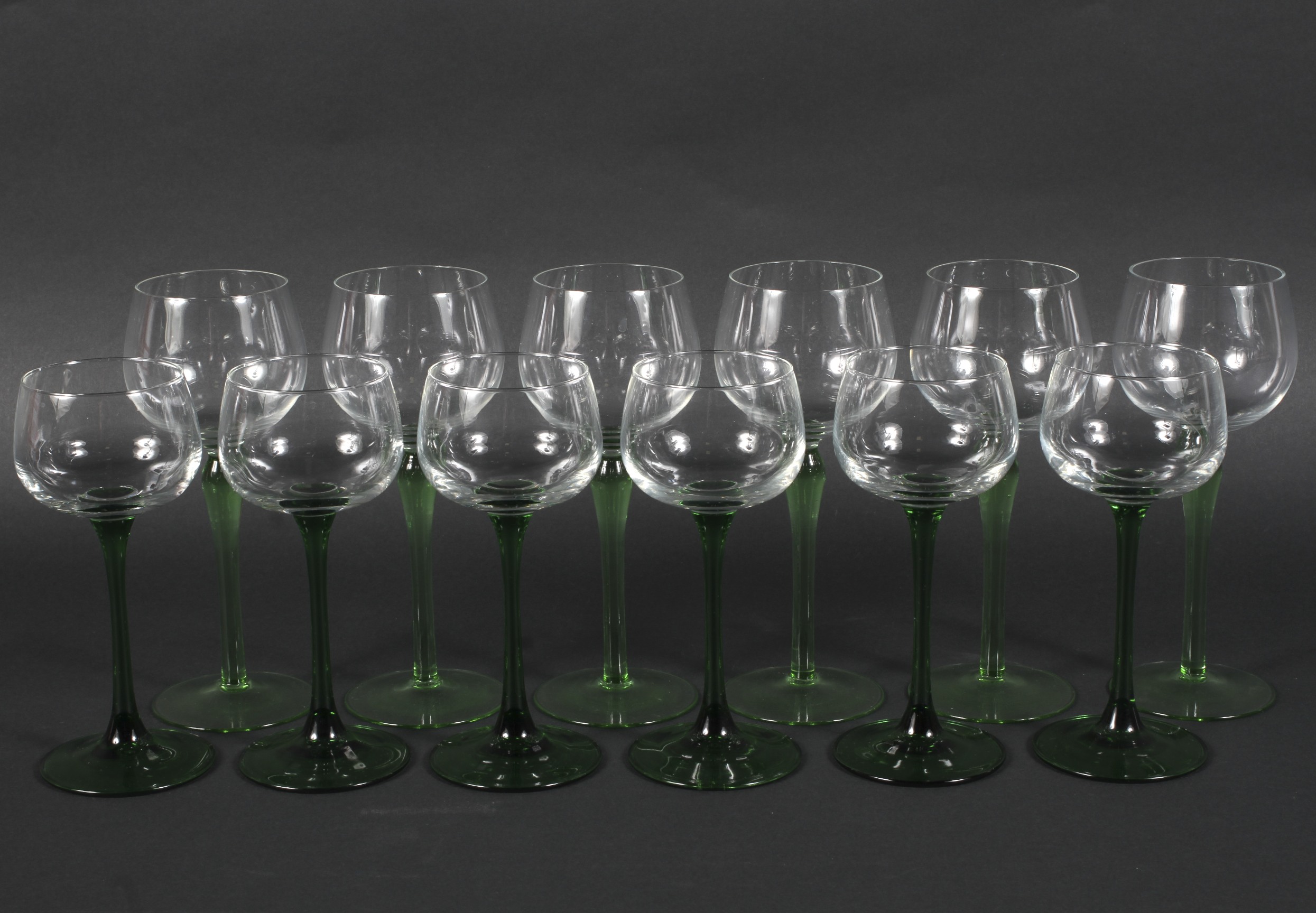 Two sets of six green stemmed glasses, on circular bases 18.5cm & 16.