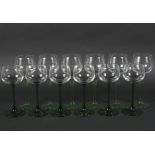 Two sets of six green stemmed glasses, on circular bases 18.5cm & 16.