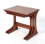 A 1970's teak nest of three tables with shaped supports united by a stretcher,