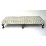 An upholstered footstool, raised on wooden cabriole supports,