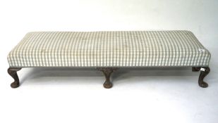 An upholstered footstool, raised on wooden cabriole supports,