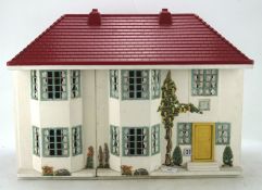 A vintage Tri-ang style doll's house, with red plastic roof and sliding metal front,