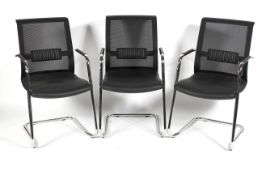 A set of three chrome and faux leather dining chairs with mesh backs in the Pieff style,