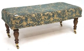 A 20th century upholstered footstall, on turned supports with castors,