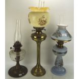 Three Edwardian oil lamps, one on brass column base, one with blue glass body and shade,