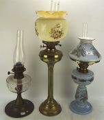 Three Edwardian oil lamps, one on brass column base, one with blue glass body and shade,