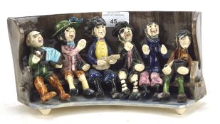 An Alan Young (Norfolk) studio pottery group of pub singers seated on a settle,