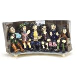 An Alan Young (Norfolk) studio pottery group of pub singers seated on a settle,