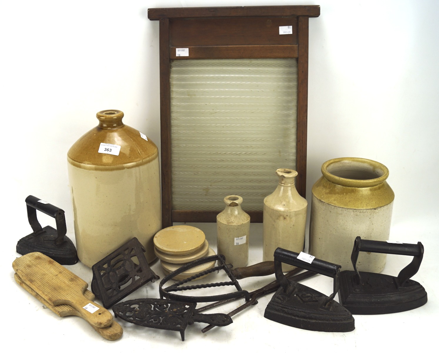 A collection of kitchenalia, including saltglazed stoneware flagons, Victorian irons,