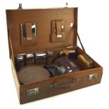 A vintage gentleman's brown leather suitcase fitted with assorted brush and grooming sets,