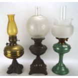 Two Edwardian oil lamps and another later, the first two on pierced metal bases,