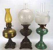 Two Edwardian oil lamps and another later, the first two on pierced metal bases,