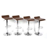 A set of four chrome revolving adjustable bar stools, with brown leatherette and foot bar seats,