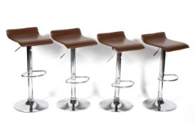 A set of four chrome revolving adjustable bar stools, with brown leatherette and foot bar seats,