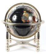 A table top globe mounted with semi-precious stones, within a brass frame,