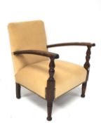 A 1930s oak elbow chair, upholstered in cream suede, raised on turned front supports on pad feet,
