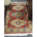 A 20th century Middle Eastern floor rug, with geometric decoration on a red ground,