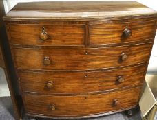 A mahogany bow fronted chest of two short over three long drawers, with turned wooden handles,