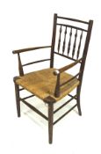 A 20th century Arts and Crafts armchair, with wicker seat and raised on turned graduating supports,
