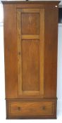 A 20th century mahogany single door wardrobe, panels to the front and sides with a drawer beneath,