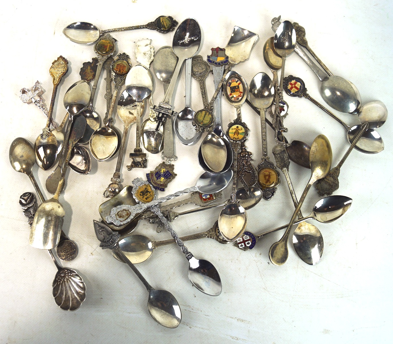 A large selection of vintage commemorative teaspoons, featuring countries, tourist sites,