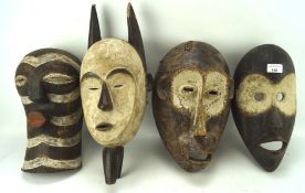 Four African carved and painted wooden tribal masks,