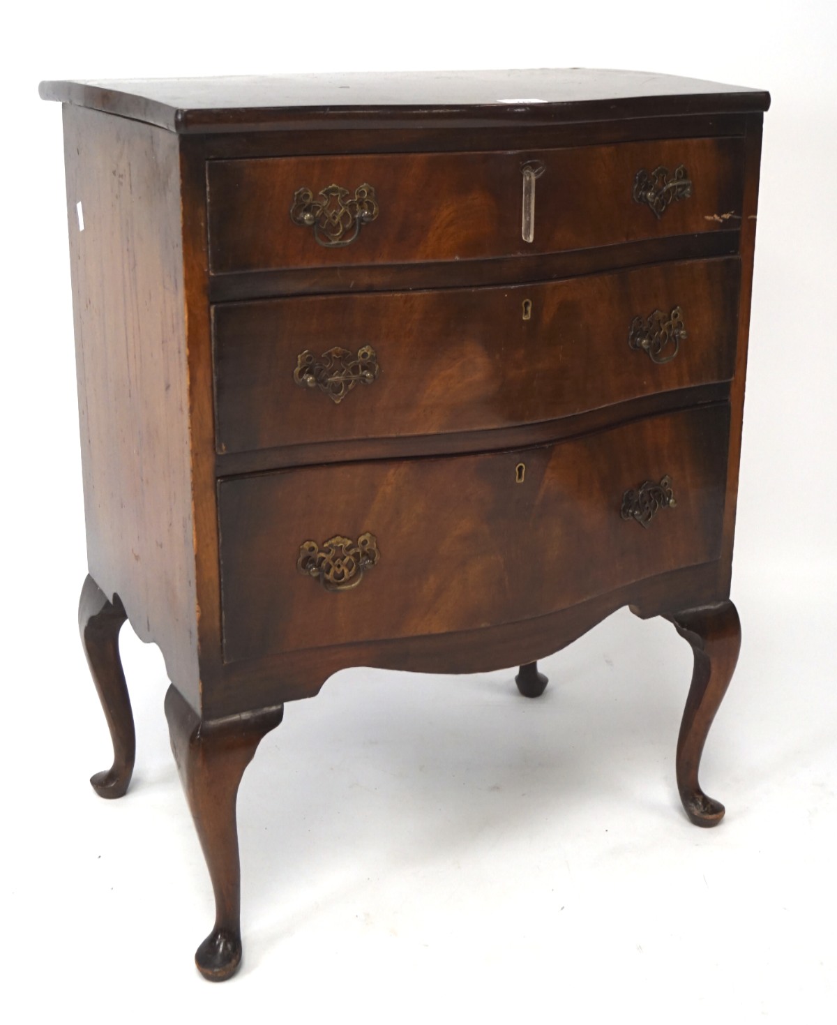 A 20th century veneered mahogany chest of three graduating drawers, of serpentine form,