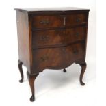 A 20th century veneered mahogany chest of three graduating drawers, of serpentine form,