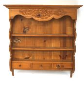 A rack of pine wall shelves with two shelves over three drawers, all beneath a carved, shaped panel,