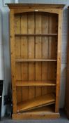 A contemporary pine bookcase, with adjustable shelves and panels to either side, on plinth base,