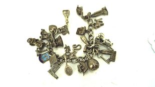 A continental white metal charm bracelet with a selection of charms, some being marked silver,